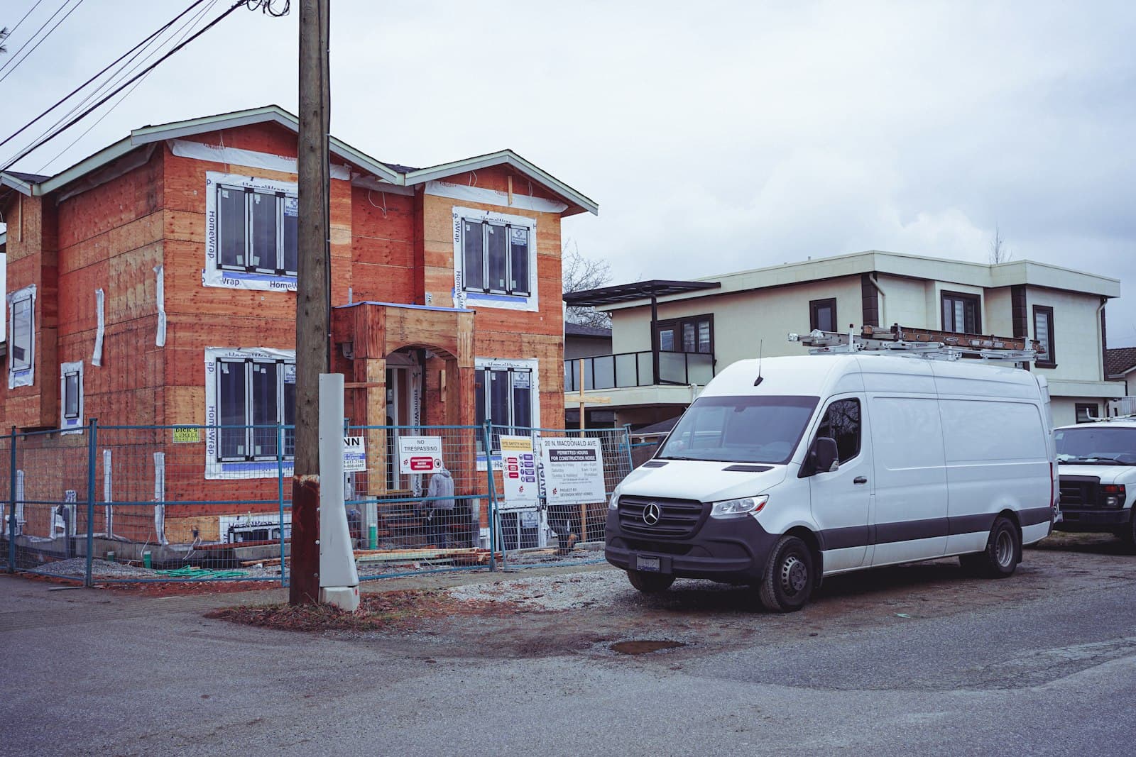 A white work van with a ladder rack parked outside a house