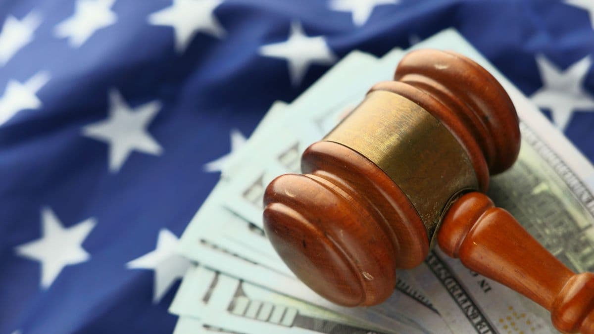 A wooden gavel resting on cash, representing contractor fraud