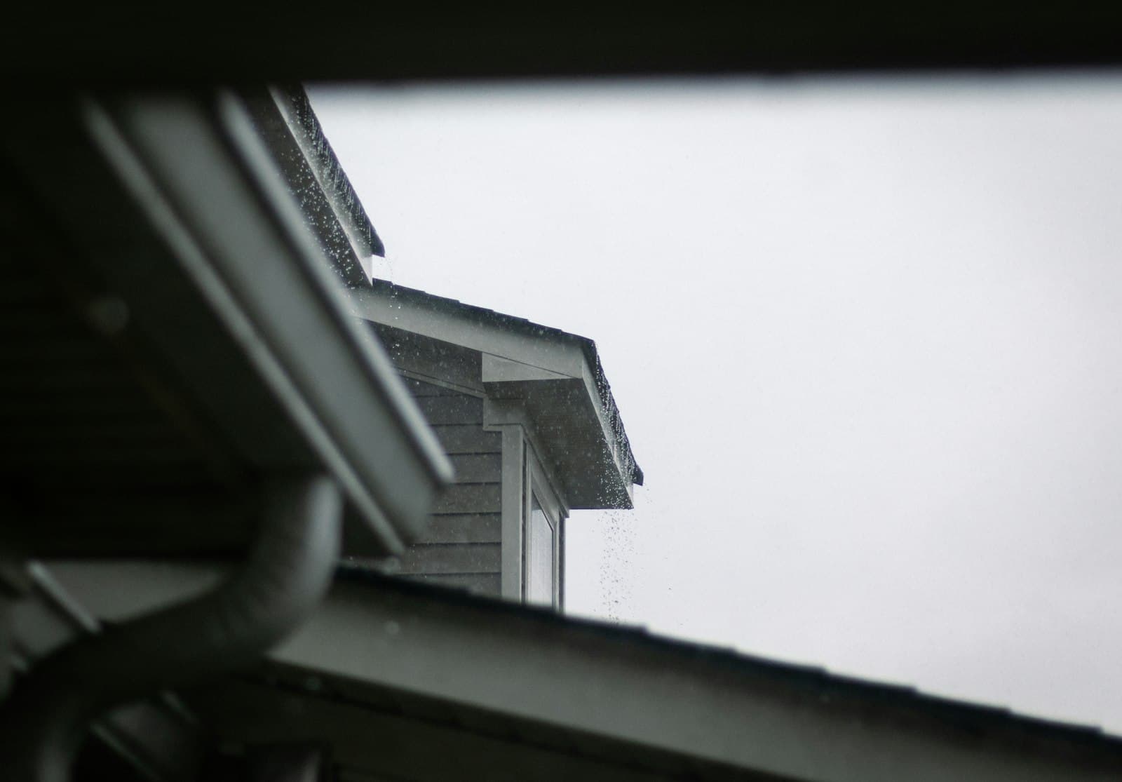 A roofline and gutter system under a grey sky